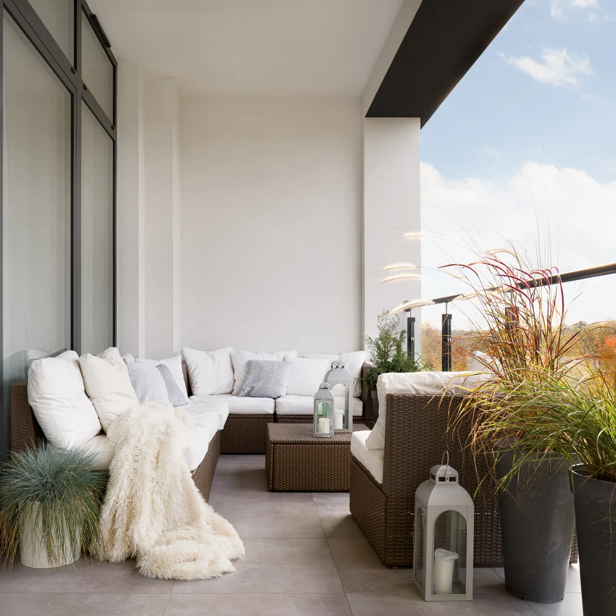 Terrace with a white outdoor sofa, lanterns and planters