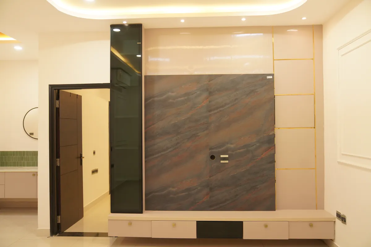 Living room TV wall in grey-brown stone-look panelling with smoked glass, brass inlay lines and a cove-lit ceiling